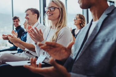 Team of businesspeople clapping hands while having a conference. Business professionals applauding at a seminar. - JLPSF15456