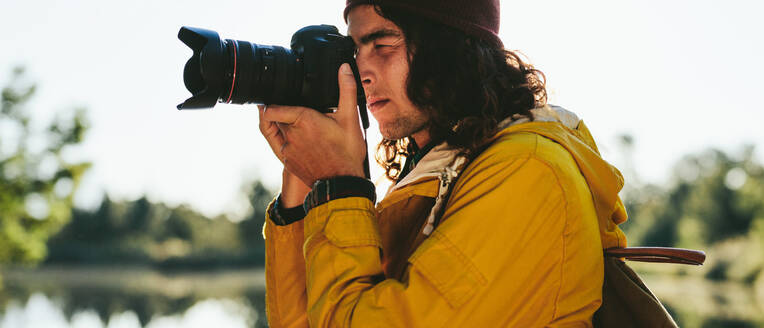 Nahaufnahme eines Mannes, der ein Foto mit einer Digitalkamera macht. Ausschnitt eines Touristen, der in seine DSLR-Kamera schaut, um ein Foto zu machen. - JLPSF15496