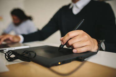 Close up of a man writing on a digital writing pad using a digital pen. Tech savvy man using modern gadget to input data. - JLPSF15516