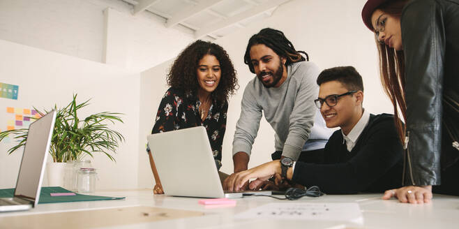 Kreative Geschäftskollegen, die ihre Arbeit an einem Laptop im Team besprechen. Geschäftsleute, die zusammenarbeiten und Ideen im Büro austauschen. - JLPSF15519