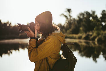 Tourist, der ein Foto mit einer DSLR-Kamera macht. Seitenansicht eines Reisenden, der in seine Digitalkamera schaut, um ein Foto zu machen. - JLPSF15571