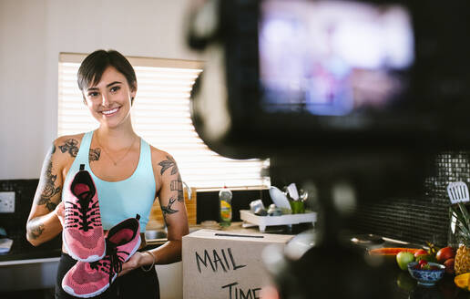 Female vloggers making video at home about sports shoes. Woman vlogger unboxing a sports shoe and recording review on camera. - JLPSF15634