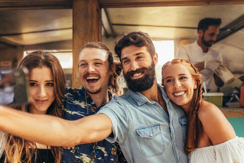 Hübscher junger Mann macht Selfie mit Freunden. Gruppe von Männern und Frauen macht Selfie beim Sommerfest. - JLPSF15660