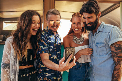 Eine Gruppe junger Leute macht ein Selfie mit dem Handy im Freien. Zwei Paare schauen in die Kamera für ein Selfie. - JLPSF15663