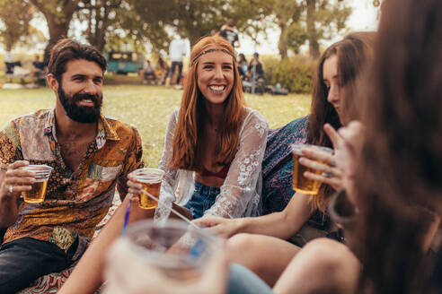 Junge Hippie-Freunde feiern im Park mit Bier. Eine Gruppe von Freunden feiert eine Party auf einem Musikfestival im Park. - JLPSF15682