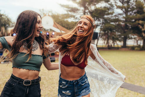 Zwei junge Frauen lächeln und haben eine tolle Zeit auf einem Musikfestival. Freundinnen in Sommerkleidung genießen auf einem Musikfestival. - JLPSF15691