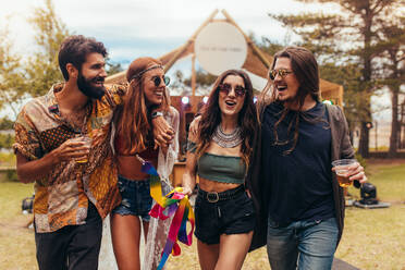 Eine Gruppe von Männern und Frauen auf einem Musikfestival, die Bier trinken und sich amüsieren. Freunde, die sich auf einem Musikfestival in einem Park amüsieren. - JLPSF15693