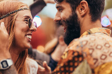 Close up of young couple dancing at music festival. Man and woman in hippie style having fun outdoors. - JLPSF15705