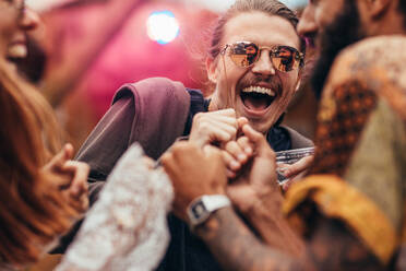 Cheerful man dancing with friends at music festival. Group of people having a great time at music festival. - JLPSF15708