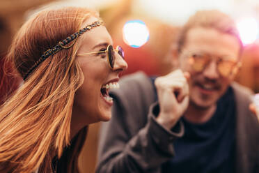 Beautiful woman in hippie style with sunglasses dancing and enjoying with friends at music festival. Young people having fun at music festival. - JLPSF15709