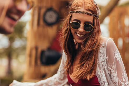 Glückliche junge Hippie-Frau, die auf einem Musikfestival im Freien tanzt. Weiblicher Hipster mit Sonnenbrille, der auf einem Musikfestival Spaß hat. - JLPSF15712