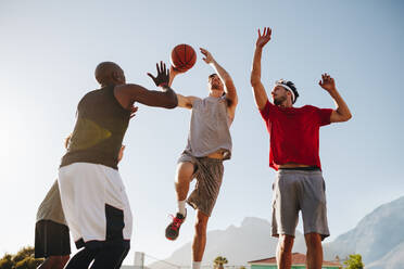 Männer spielen Basketball an einem sonnigen Tag und üben sich im Dribbeln. - JLPSF15730