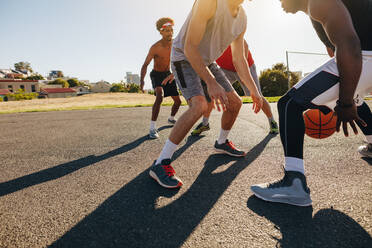 Männer spielen Basketball an einem sonnigen Tag. Männer üben Basketball im Spielbereich. - JLPSF15732