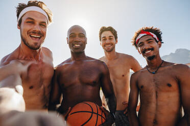 Vier Männer posieren für ein Selfie mit einem Basketball. Lächelnde junge Männer posieren für ein Foto. - JLPSF15738