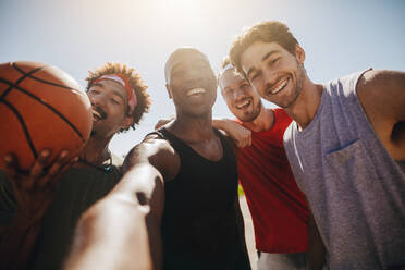 Vier Männer posieren für ein Selfie mit einem Basketball. Männer genießen beim Basketball spielen. - JLPSF15762