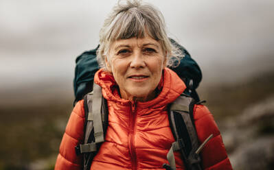 Nahaufnahme einer älteren Frau, die eine Jacke trägt und einen Rucksack mit sich führt. Ältere Frau auf einer Wanderung an einem Wintertag. - JLPSF15799