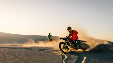 Motocross riders driving their bikes on the sand dune. Dirt bikers off roading in desert. - JLPSF15857