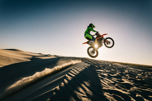 Professionelle Motocross-Rennfahrer springen über die Düne auf Off-Road-Strecke. Dirt-Biker reiten mitten in der Luft über eine Sanddüne in der Wüste. - JLPSF15886