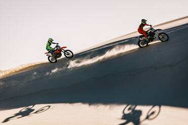 Dirt bikers riding motorcycles on sand dunes in a competition. Motocross racers racing in desert. - JLPSF15896