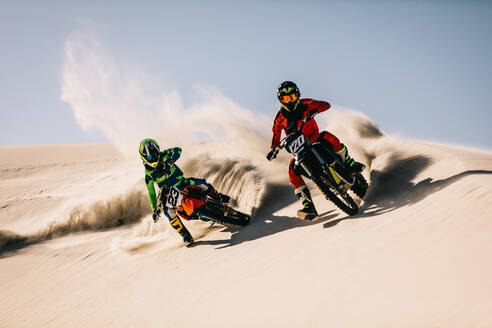Zwei Motocross-Fahrer rasen über die Sanddünen. Dirt-Biker beschleunigen schnell in der Wüste. - JLPSF15897