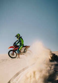 Dirt Bike auf einer Sanddüne mit einer Spur von herumfliegendem Geröll, Vollgas in der Wüste. - JLPSF15900