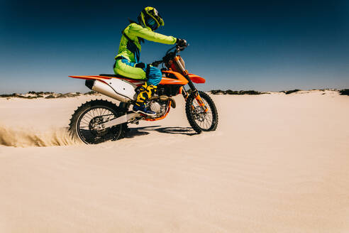 Motocross-Fahrer, der sein Rad auf Sand dreht. Dirt-Biker, der Sand aufwirbelt und Spaß hat, während er über Sanddünen fährt. - JLPSF15901