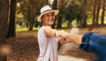 Point of view shot von romantischen Paar zu Fuß im Park zusammen. Mann hält die Hände seine glückliche Freundin trägt einen Hut und lächelnd. Point of view shot. - JLPSF15911