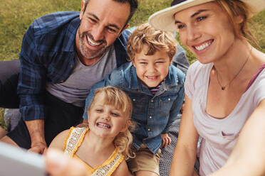 Beautiful woman with family on picnic talking selfie at park. Couple with their two children making a self portrait at park. - JLPSF15921