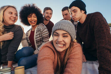 Eine Gruppe junger Leute macht lustige Gesichter, während sie ein Selfie am Strand machen. Junge Leute genießen es, zusammen am Strand ein Selbstporträt zu machen. - JLPSF15932