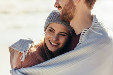 Close up of woman being embraced by her boyfriend outdoors at the sea shore. Romantic couple standing at the beach. - JLPSF15961