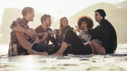 Young man playing guitar for friends on the beach. Group of friends having party at the seashore. - JLPSF15968