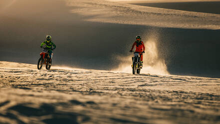 Two riders racing in motocross race. Dirt bikers racing on sand dunes. - JLPSF16021