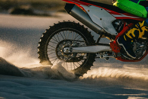 Nahaufnahme eines Motocross-Rads auf einer Sanddüne. Fliegende Trümmer während einer Beschleunigung bei einer Motocross-Fahrt. - JLPSF16026