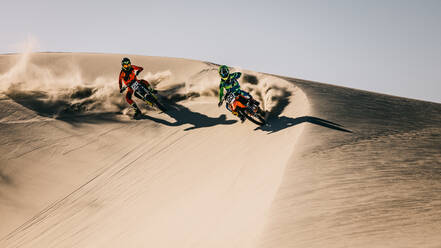 Motocross competition over dunes in desert. Motor bike riders accelerating over sand dunes. - JLPSF16032
