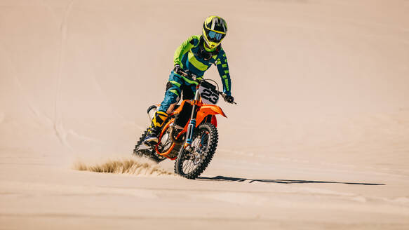 Motorradfahrer fährt aufrecht über Sand in der Wüste. Motocross-Biker fährt Motorrad über Sanddünen. - JLPSF16041