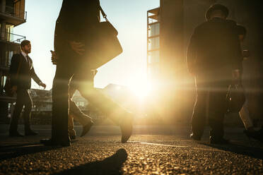 Menschen zu Fuß auf der Straße mit Sonne Flare in den Hintergrund. Männer pendeln ins Büro früh am Morgen mit Büro Taschen. - JLPSF16053