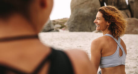 Frauen üben Yoga am Strand sitzend. Rückansicht von glücklichen Frauen in Fitnesskleidung, die sich am Strand entspannen. - JLPSF16160