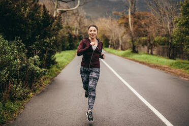 Porträt einer fitten jungen Frau, die morgens auf der Straße joggt. Frau joggt morgens im Freien. - JLPSF16242