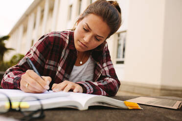 Studentin sitzt auf dem Campus und macht sich Notizen. Studentin studiert auf dem Universitätscampus. - JLPSF16251