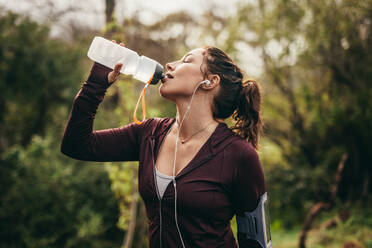 Female runner drinking water after a running working outdoors. Woman getting hydrated after running workout. - JLPSF16290