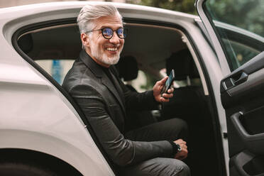 Porträt von lächelnden reifen Geschäftsmann sitzt auf dem Rücksitz eines Taxis. Mann nimmt ein Taxi für die Reise. - JLPSF16393