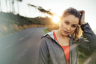 Fitness Frau läuft auf der Straße mit Sonne im Hintergrund. Porträt einer Läuferin auf einer leeren Straße am Morgen. - JLPSF16455