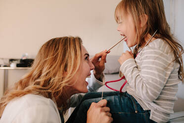 Woman doctor examining throat of little girl with spatula. Pediatrician checking throat of a girl child. - JLPSF16490