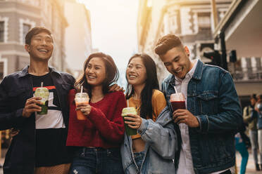Group of young asian people walking on the city street with juice. Multi-ethnic young men and women on city street with juice. - JLPSF16508