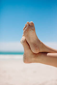 Nahaufnahme der Füße einer Person, die sich an einem Strand entspannt. Ausschnitt der Beine einer Person, die sich an einem sonnigen Tag am Strand entspannt. - JLPSF16563