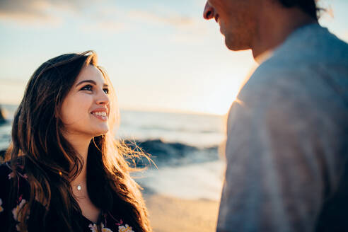 Pärchen bei einem Date im Freien am Strand. Junge Frau schaut ihren Freund an und lächelt. - JLPSF16604