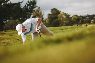 Senior-Golfer, der den Ball in den Sandbunker legt, um seinen Schlag zu machen. Profigolfer, der auf dem Golfplatz spielt. - JLPSF16687