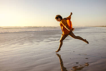 Happy woman running on the beach enjoying. Woman taking a long stride on the beach having fun. - JLPSF16737