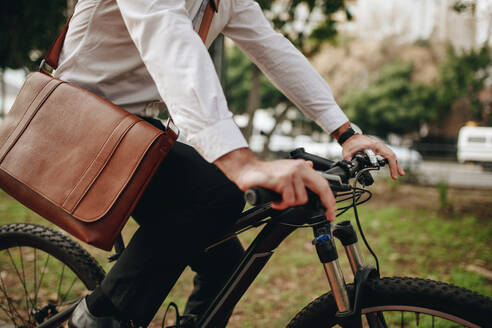 Mann mit Bürotasche auf dem Fahrrad. Geschäftsmann auf dem Weg ins Büro auf dem Fahrrad. - JLPSF16738