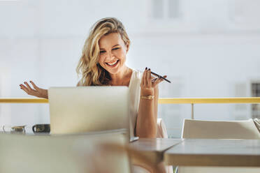 Schöne junge Frau, die auf einen Laptop schaut und lächelt, während sie in einem Café sitzt. Geschäftsfrau arbeitet an einem Laptop und lacht. - JLPSF16772